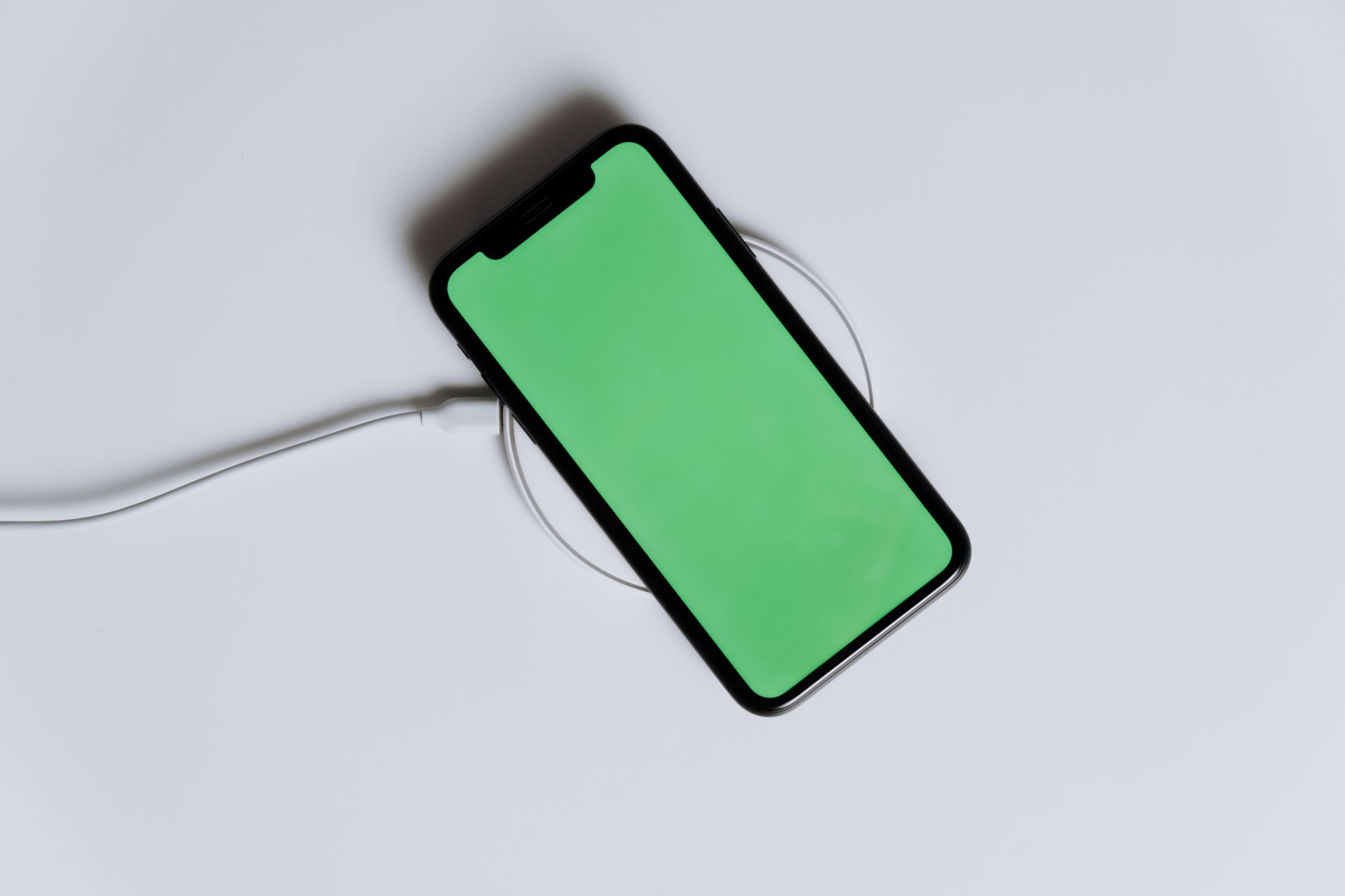 Smartphone snapping onto a magnetic Qi2 wireless charging stand on a wooden desk