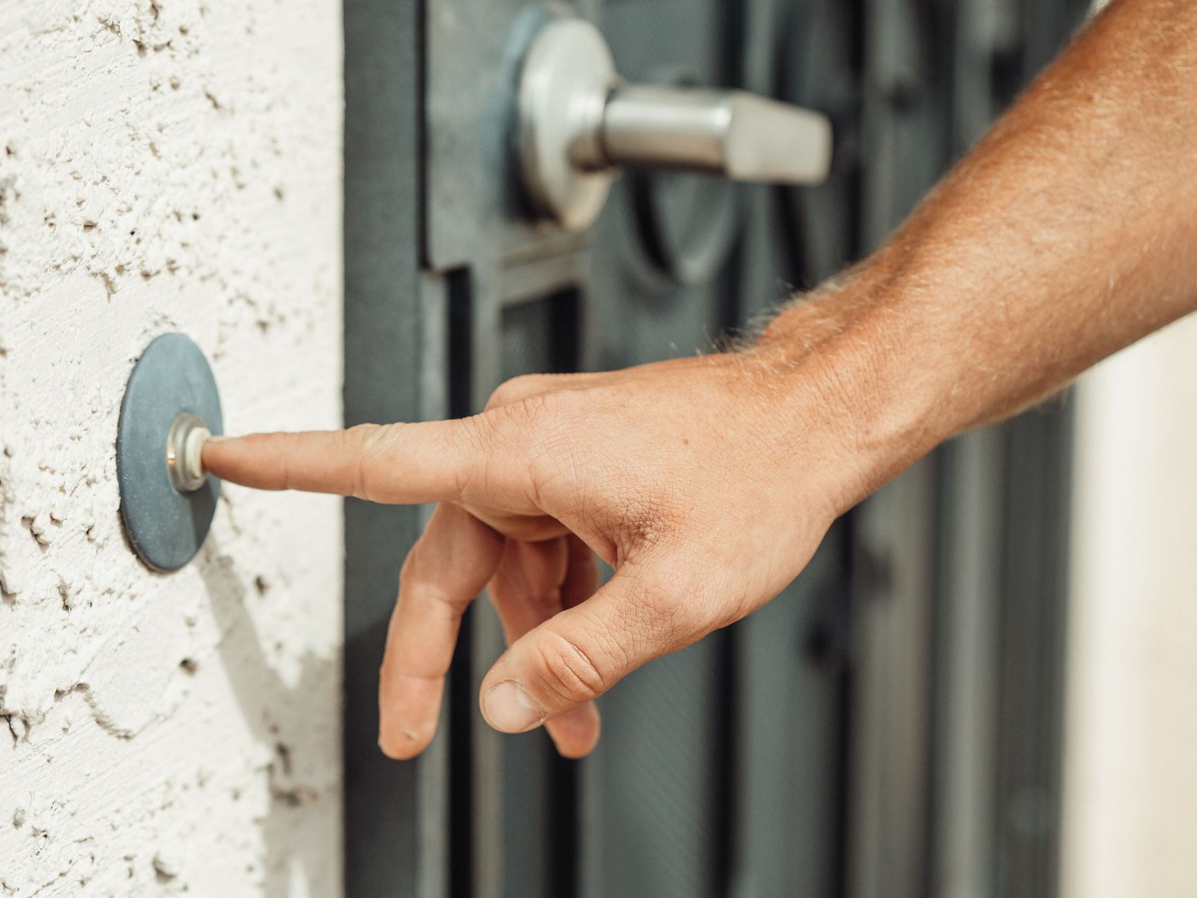 person installing video doorbell on a house exterior wall