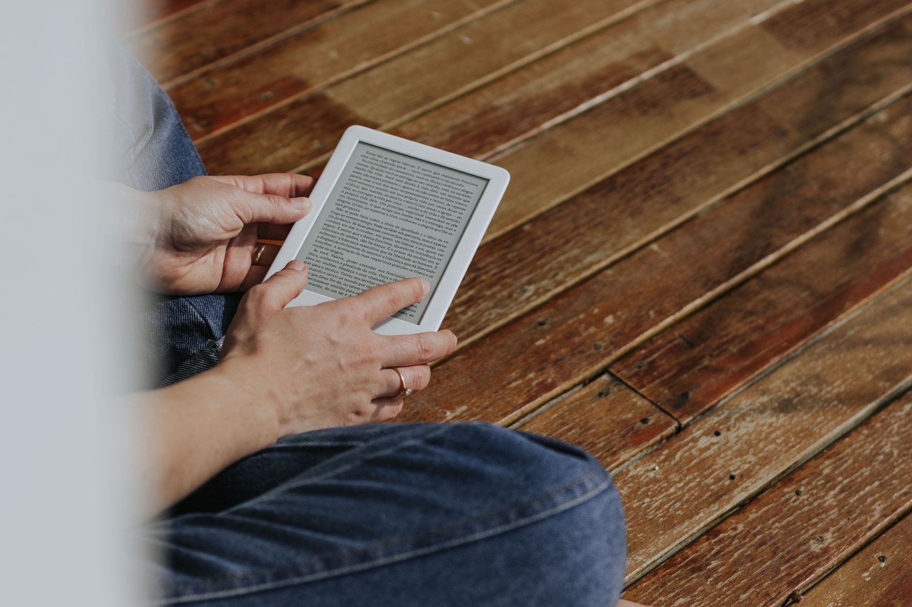 A person reading an e-reader in a cozy armchair with warm lighting