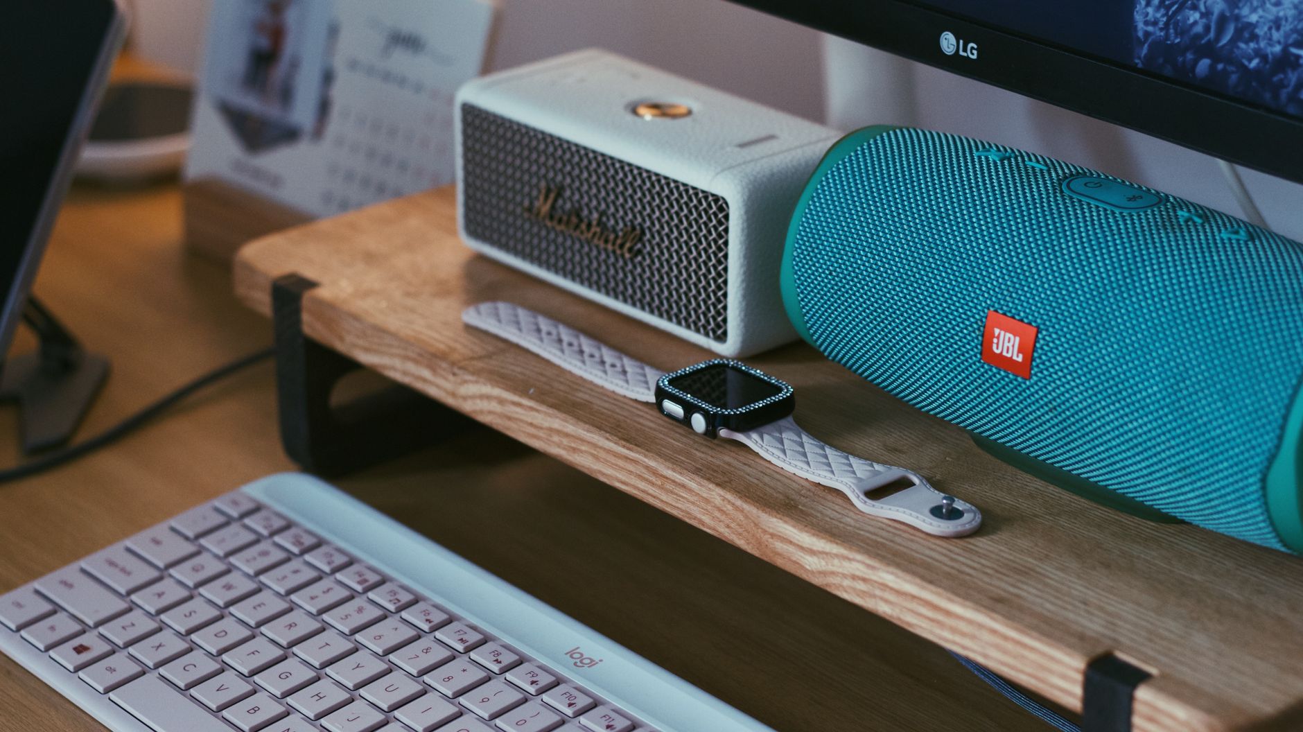 A modern portable Bluetooth speaker sitting on a clean wooden desk next to a smartphone