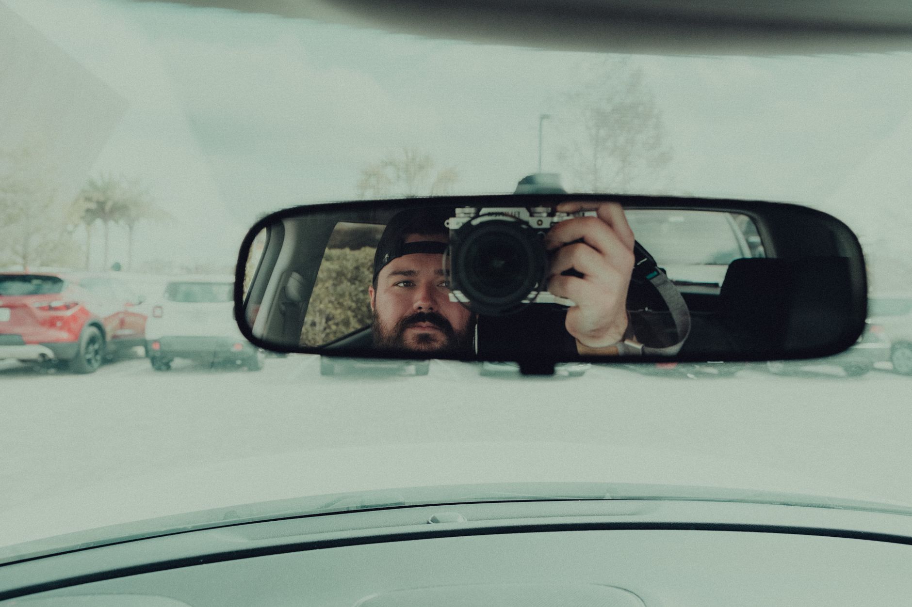 Driver installing a smart dash cam on a clear glass area behind the rearview mirror inside a car windshield