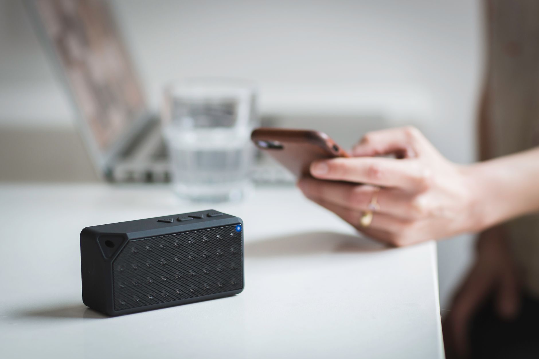 person holding smartphone next to wireless speaker